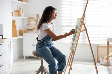 Photo of Beautiful woman drawing picture on canvas in studio