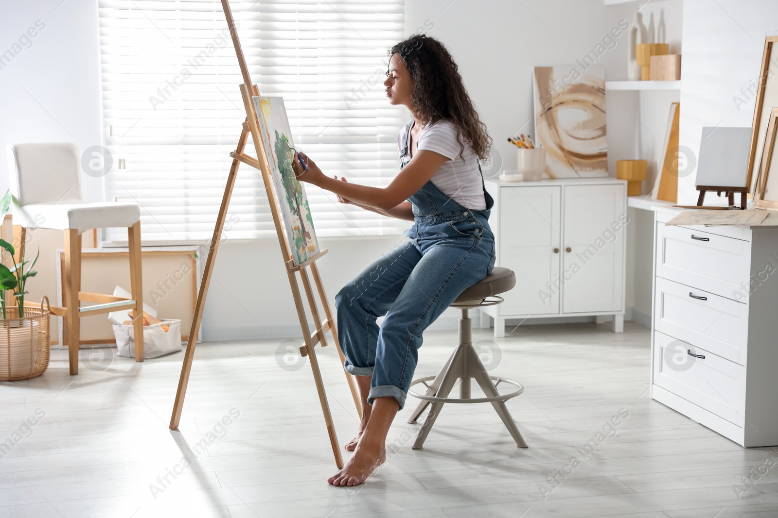 Photo of Beautiful woman drawing picture on canvas in studio