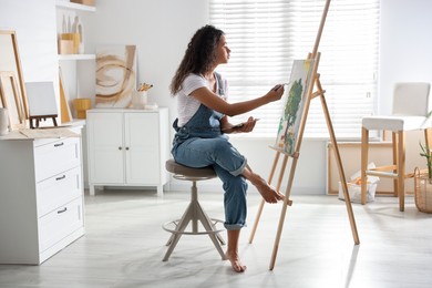 Photo of Beautiful woman drawing picture on canvas in studio