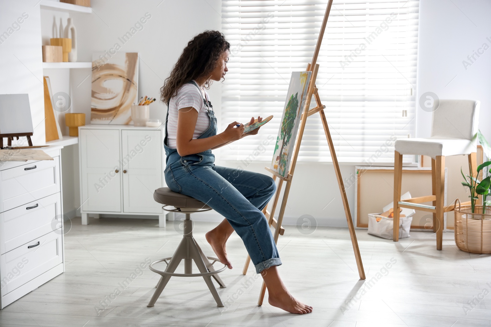 Photo of Beautiful woman drawing picture on canvas in studio