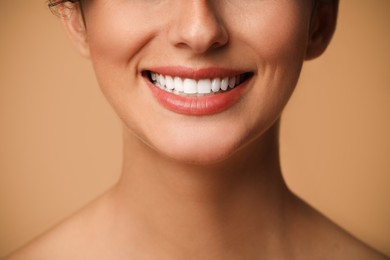 Photo of Smiling woman on beige background, closeup. Dental veneers