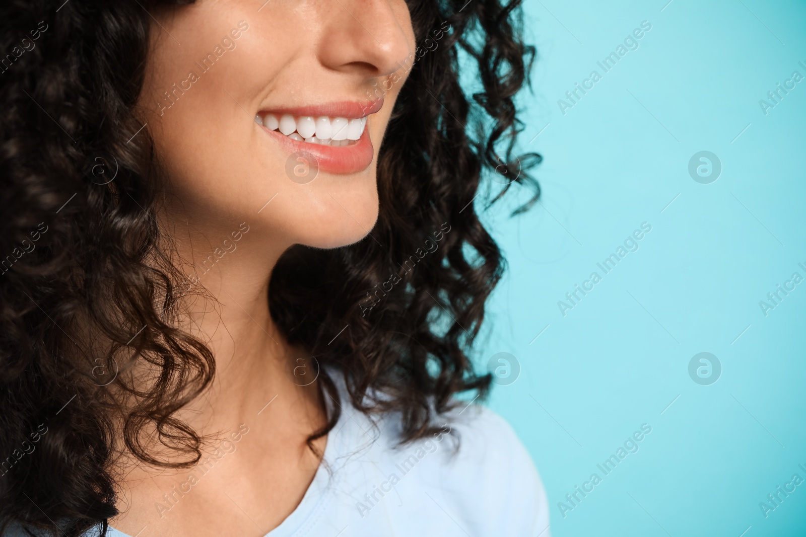 Photo of Smiling woman on light blue background, closeup. Dental veneers