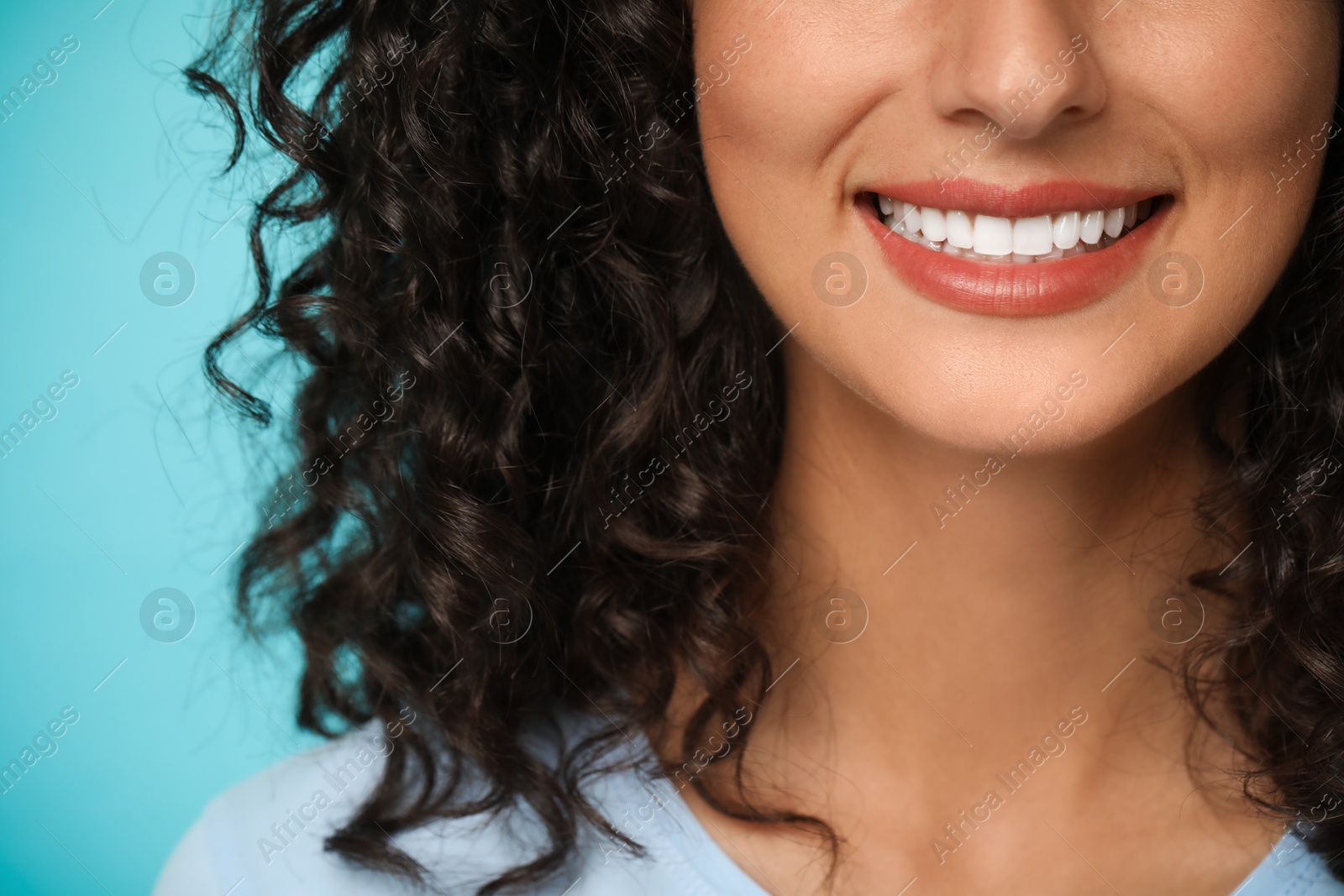 Photo of Smiling woman on light blue background, closeup. Dental veneers