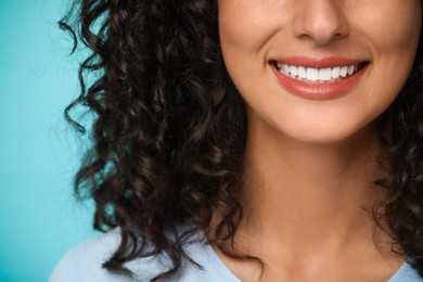 Smiling woman on light blue background, closeup. Dental veneers