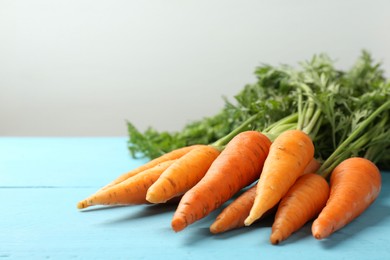 Photo of Tasty ripe juicy carrots on light blue wooden table, closeup