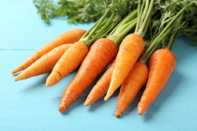 Photo of Tasty ripe juicy carrots on light blue wooden table, closeup