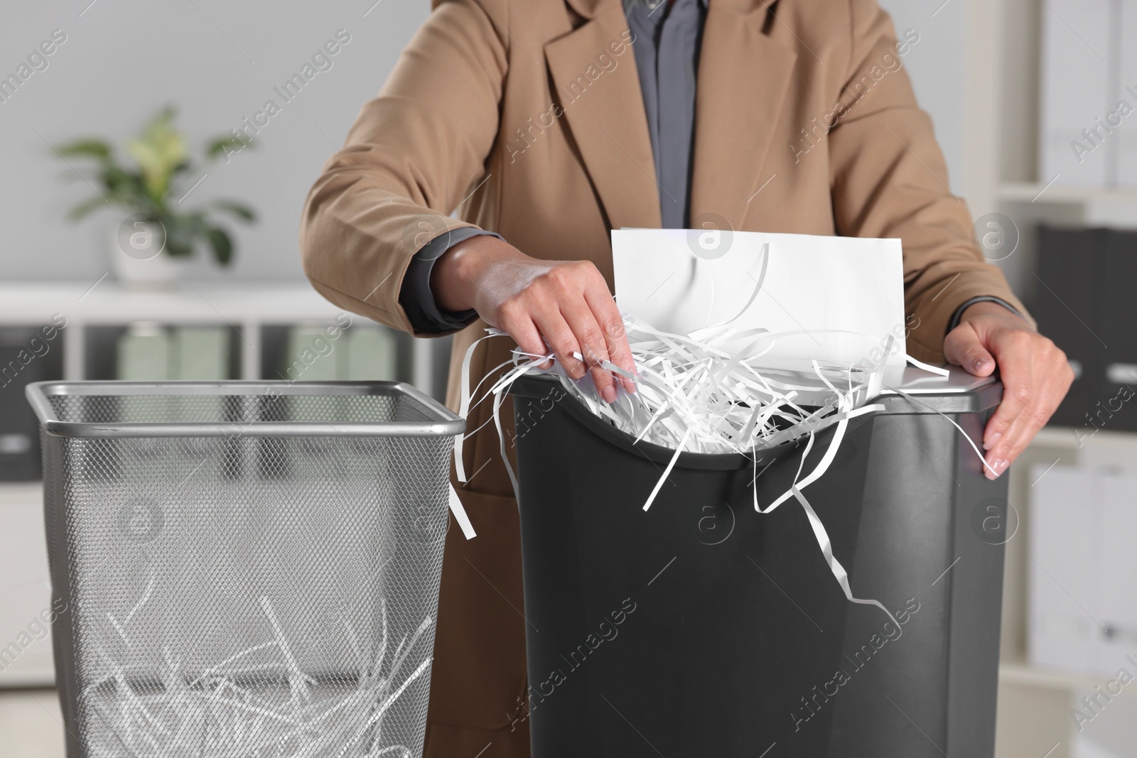 Photo of Woman destroying paper with shredder in office, closeup