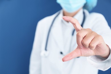 Photo of Doctor holding something on blue background, closeup. Space for text