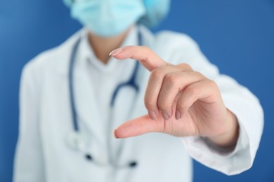 Photo of Doctor holding something on blue background, closeup