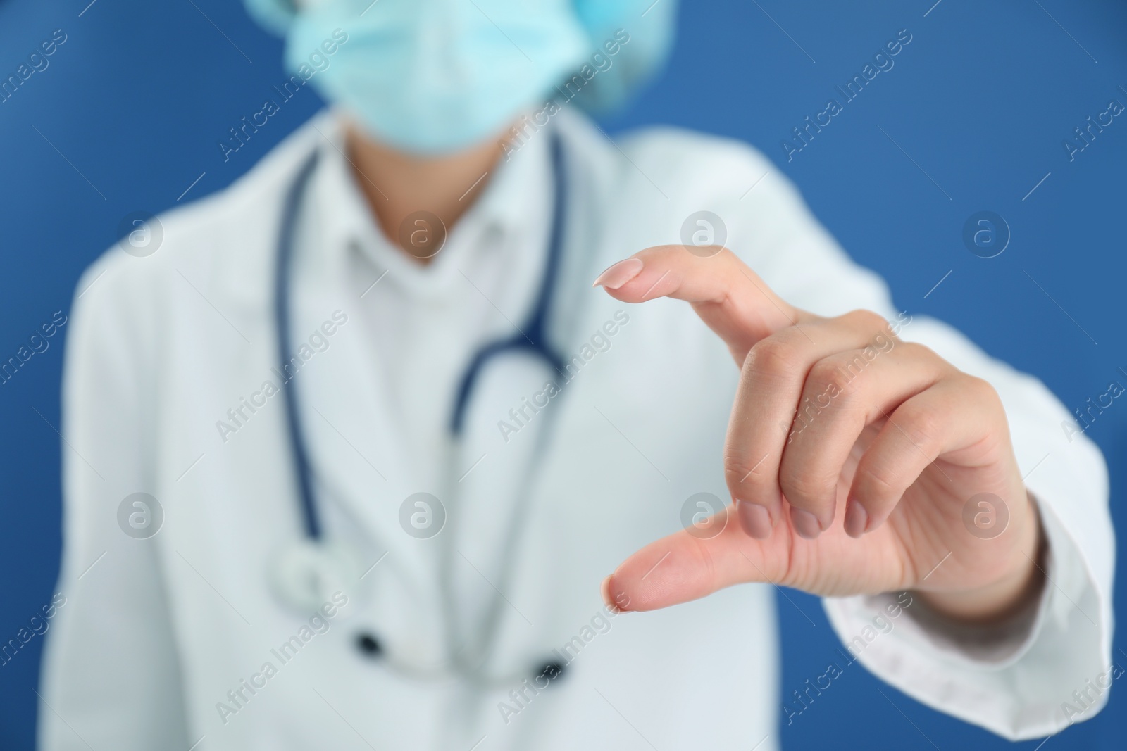 Photo of Doctor holding something on blue background, closeup