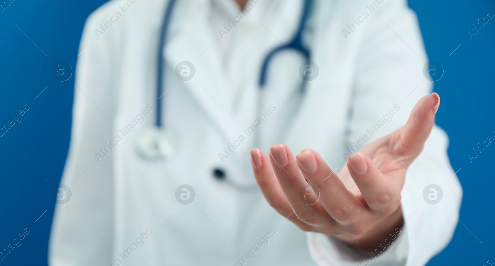 Photo of Doctor holding something on blue background, closeup