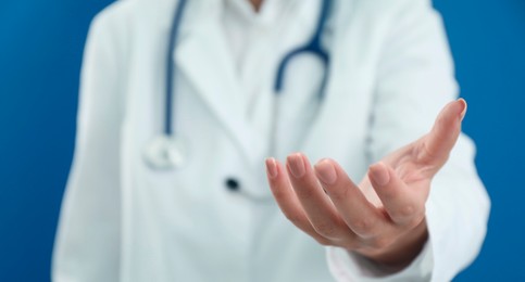 Doctor holding something on blue background, closeup