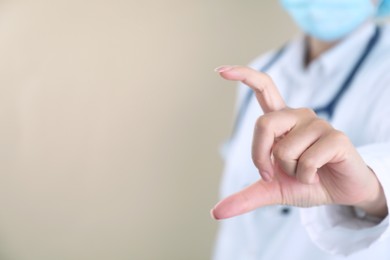 Photo of Doctor holding something on beige background, closeup. Space for text