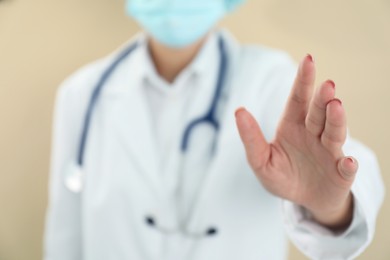 Photo of Doctor holding something on beige background, closeup