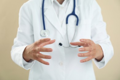 Doctor holding something on beige background, closeup