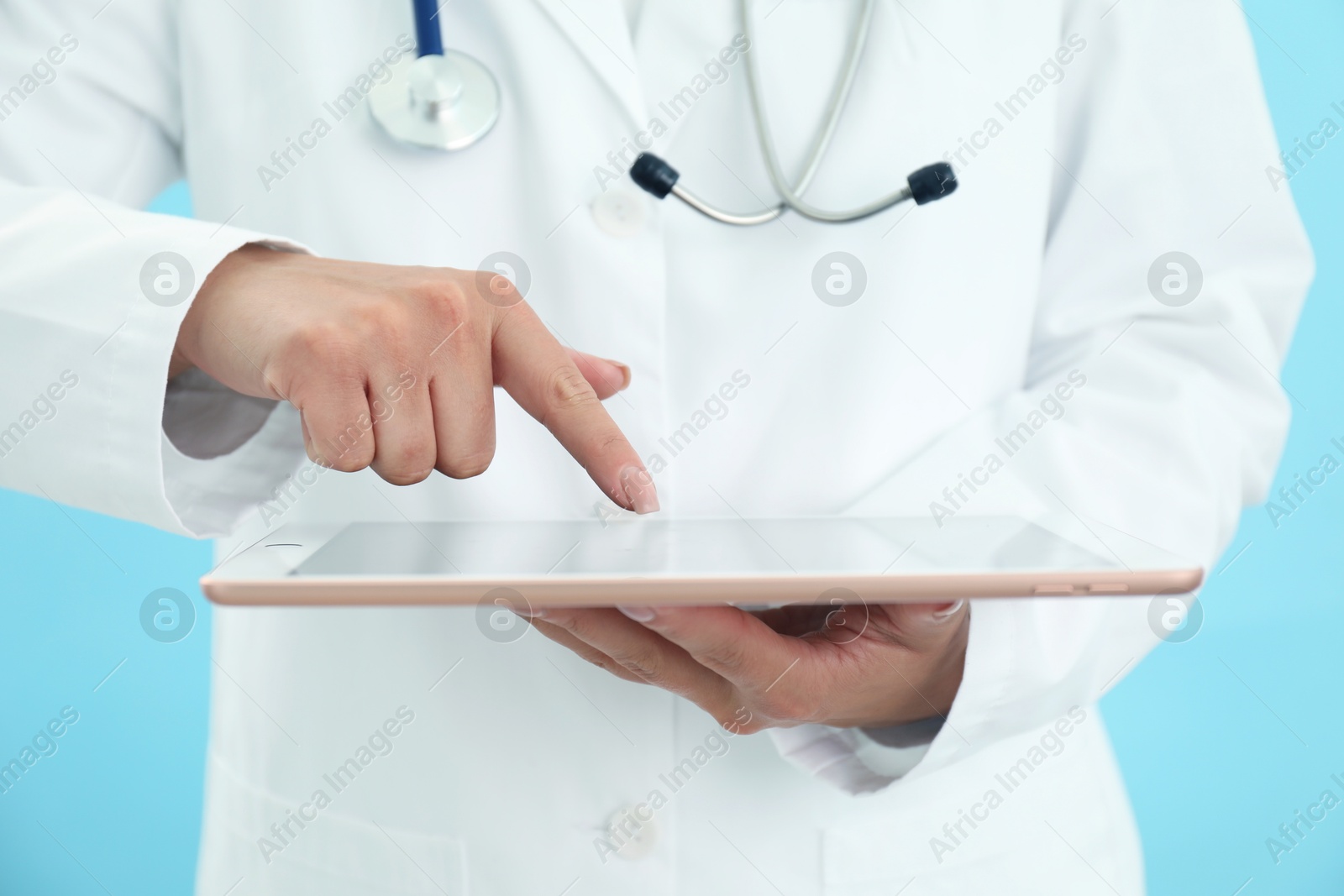 Photo of Doctor with tablet on light blue background, closeup view