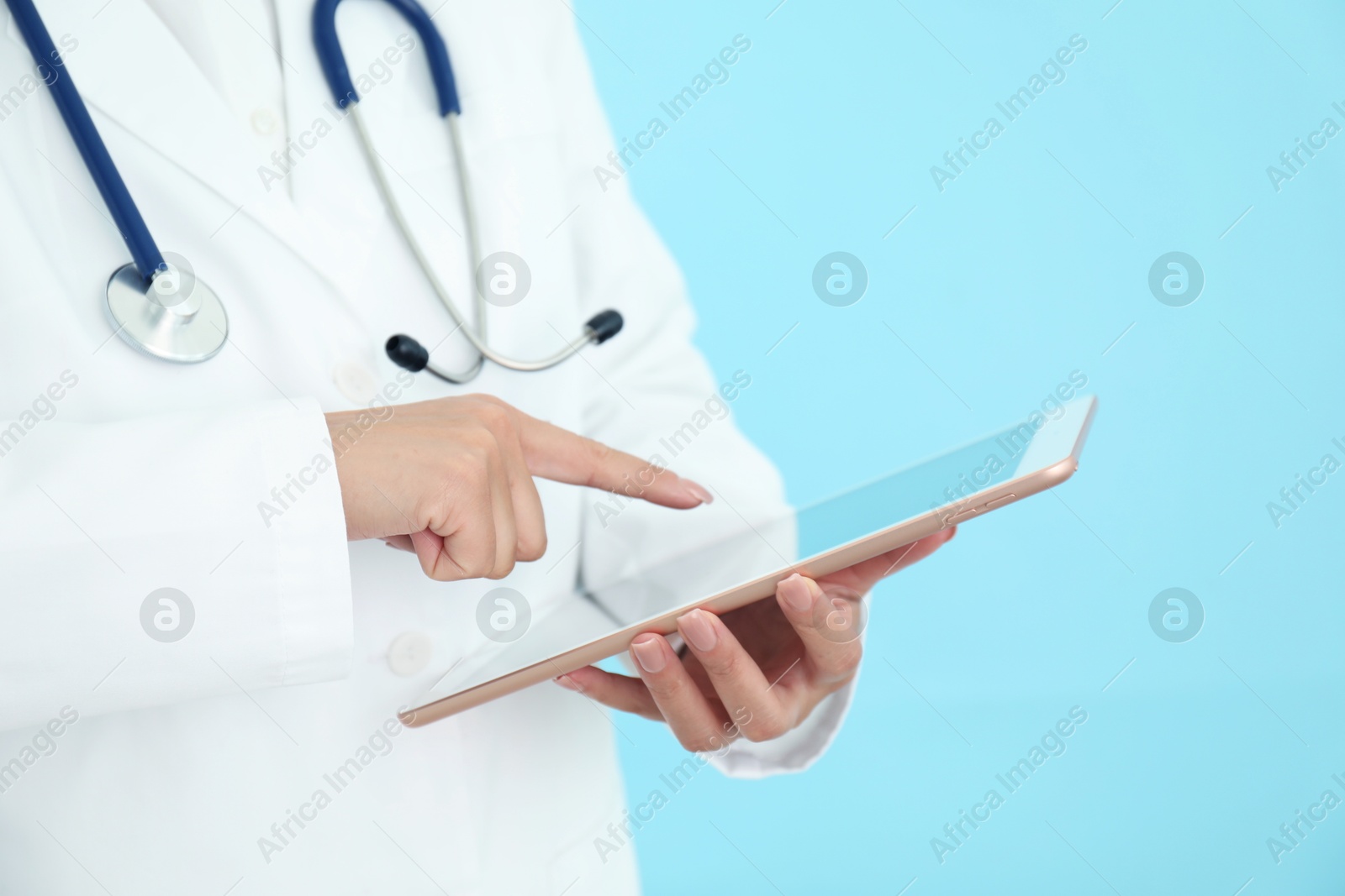 Photo of Doctor with tablet on light blue background, closeup view