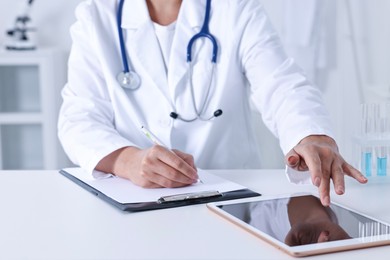 Photo of Doctor with tablet at table in clinic, closeup view