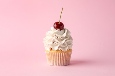 Photo of Delicious cupcake with cream and cherry on pink background