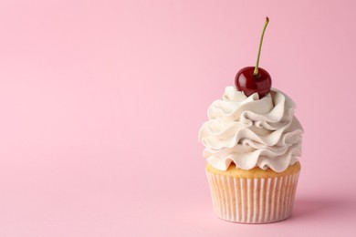 Photo of Delicious cupcake with cream and cherry on pink background, space for text