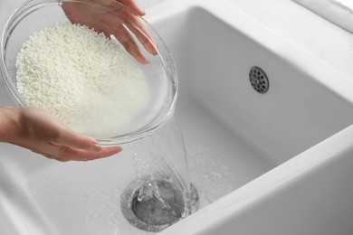 Woman rinsing rice in bowl above sink, closeup