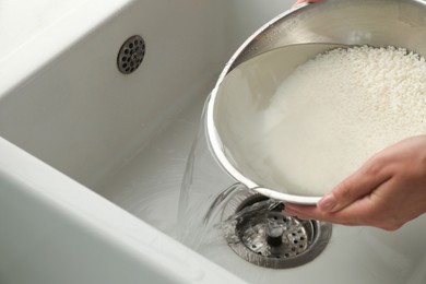 Photo of Woman rinsing rice in bowl above sink, closeup