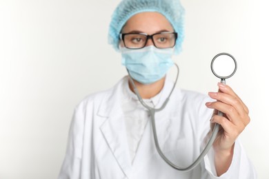 Doctor holding stethoscope on white background, selective focus