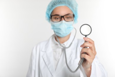 Doctor holding stethoscope on white background, selective focus