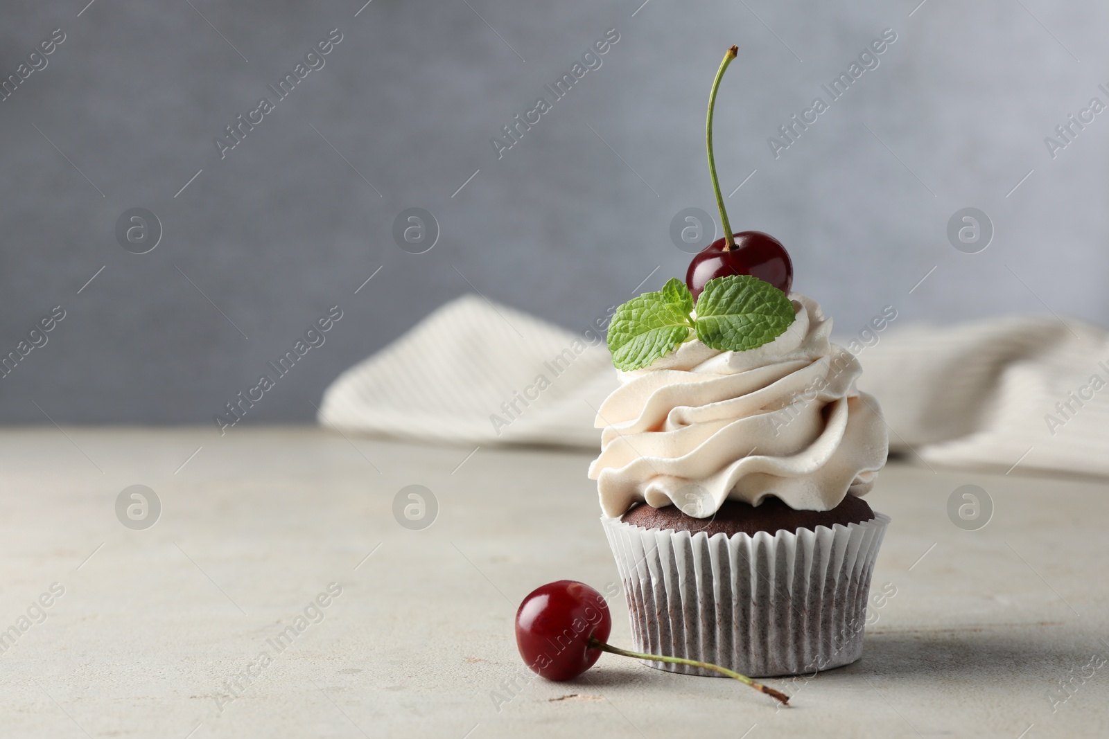 Photo of Delicious cupcake with cherries and fresh mint on light textured table. Space for text