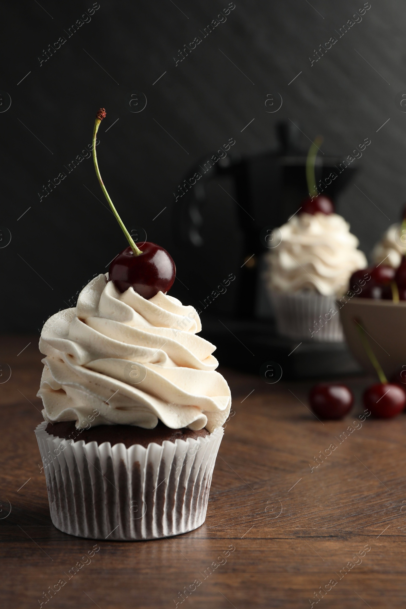 Photo of Delicious cupcake with cream and cherry on wooden table