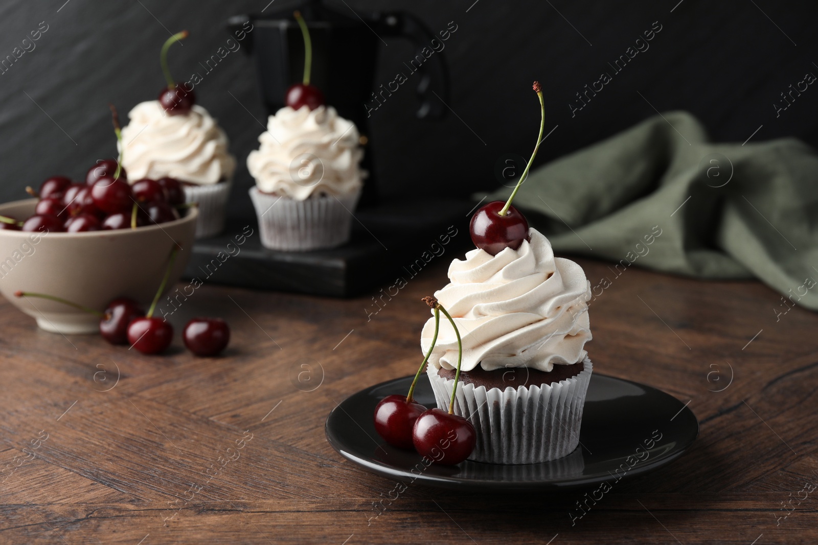 Photo of Delicious cupcakes with cream and cherries on wooden table