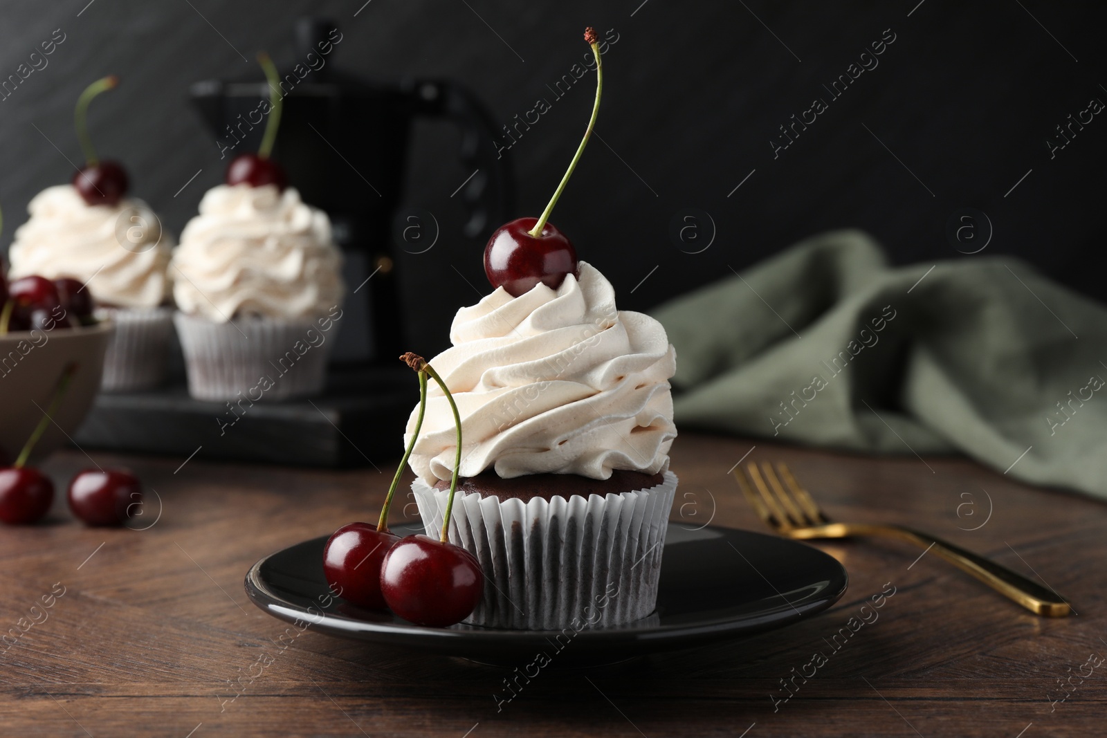 Photo of Delicious cupcakes with cream and cherries on wooden table, closeup