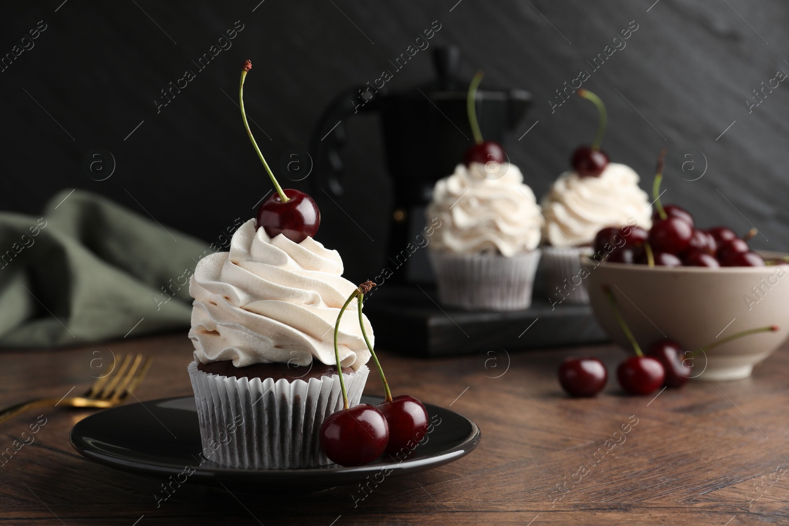 Photo of Delicious cupcakes with cream and cherries on wooden table