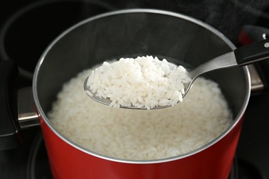 Taking boiled rice from pot with spoon, closeup