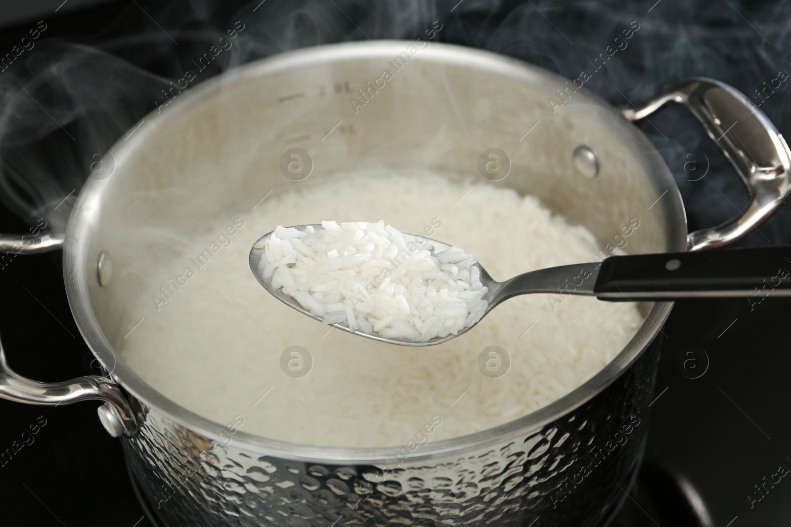 Photo of Taking boiled rice from pot with spoon, closeup