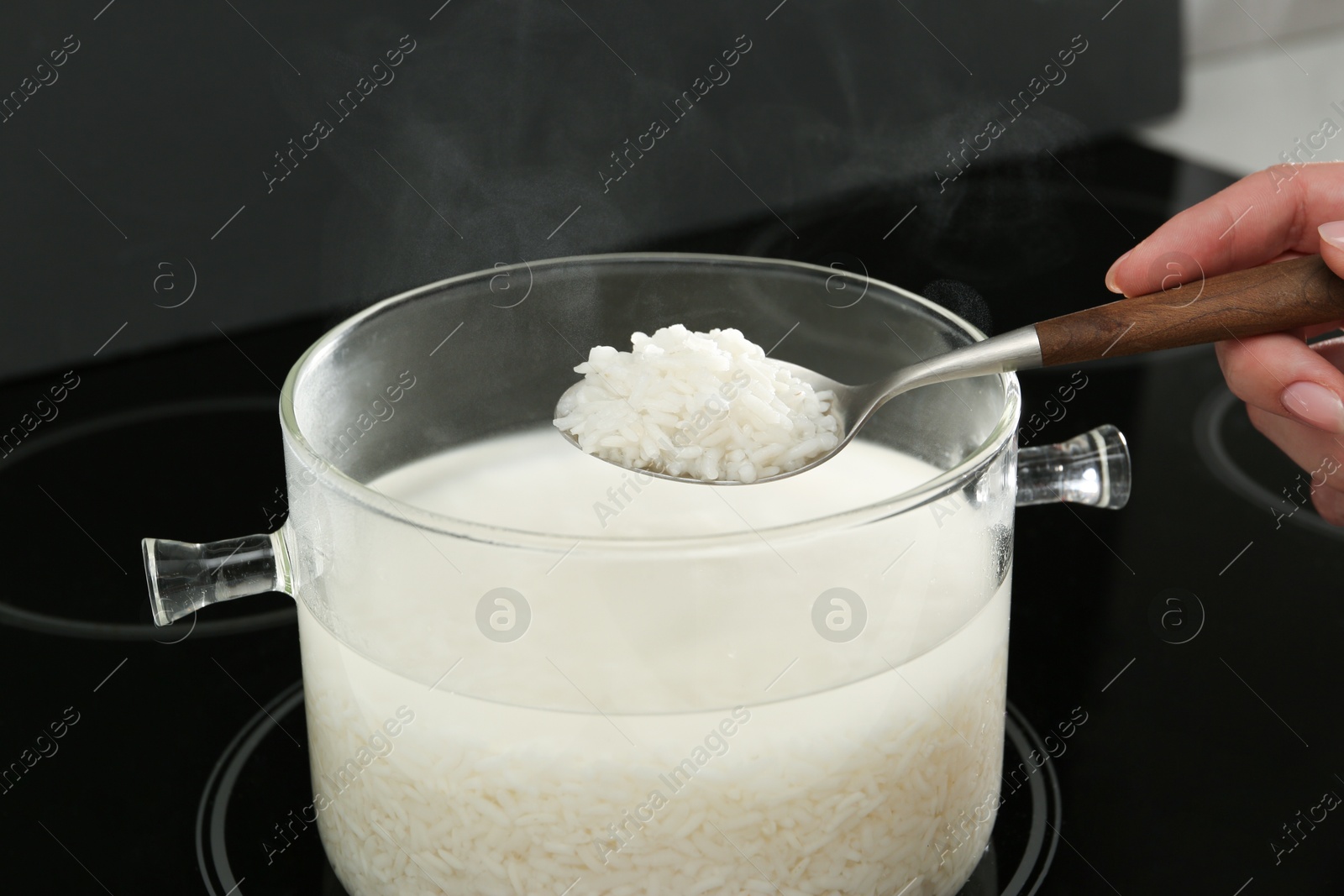 Photo of Woman taking boiled rice from pot, closeup