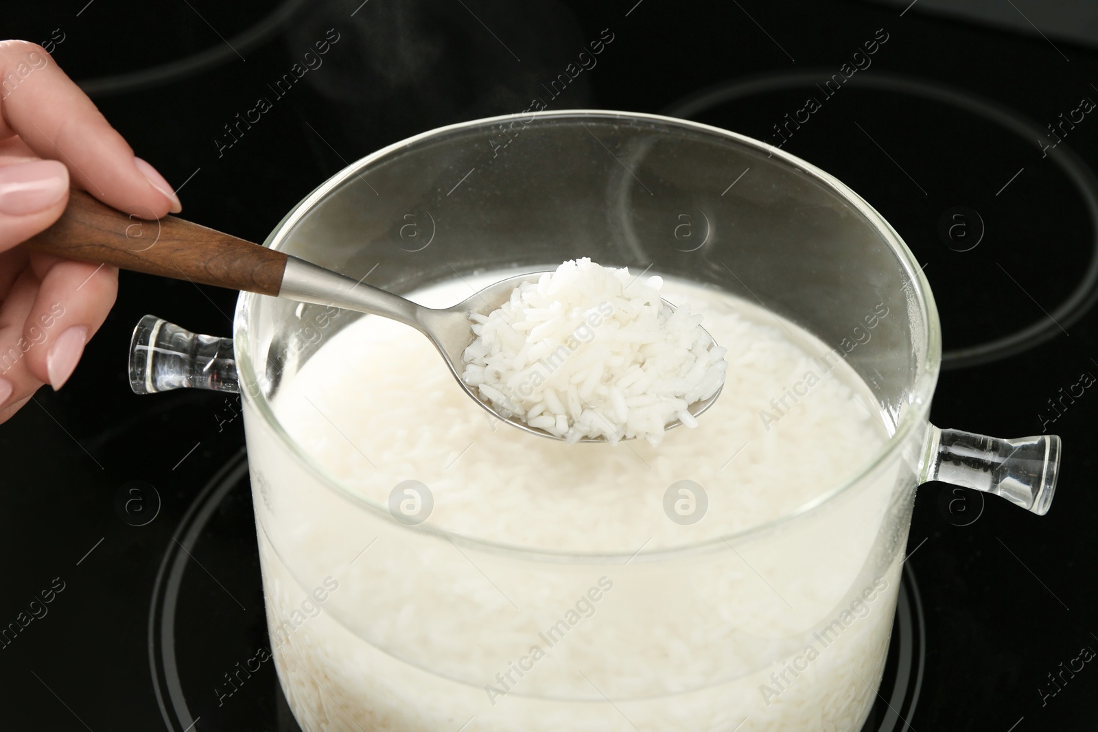 Photo of Woman taking boiled rice from pot, closeup