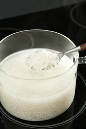 Photo of Taking boiled rice from glass pot, closeup