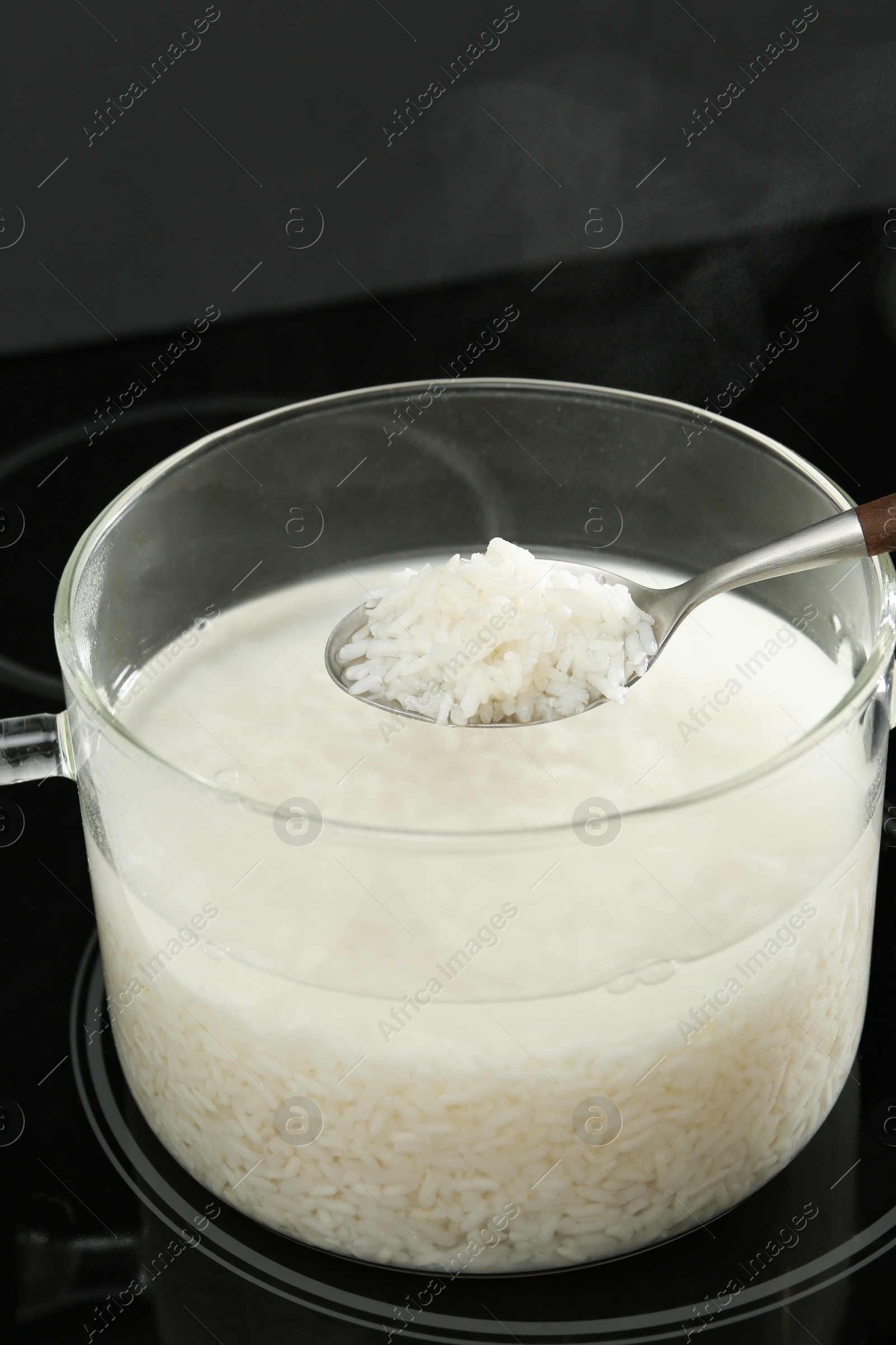 Photo of Taking boiled rice from glass pot, closeup