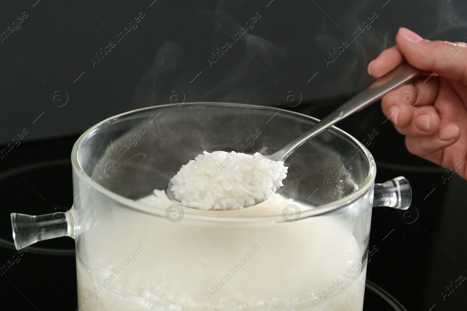 Photo of Woman taking boiled rice from pot, closeup