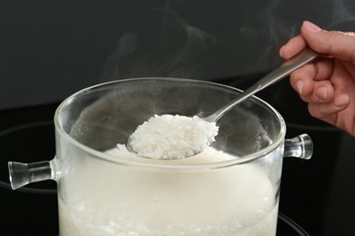 Woman taking boiled rice from pot, closeup