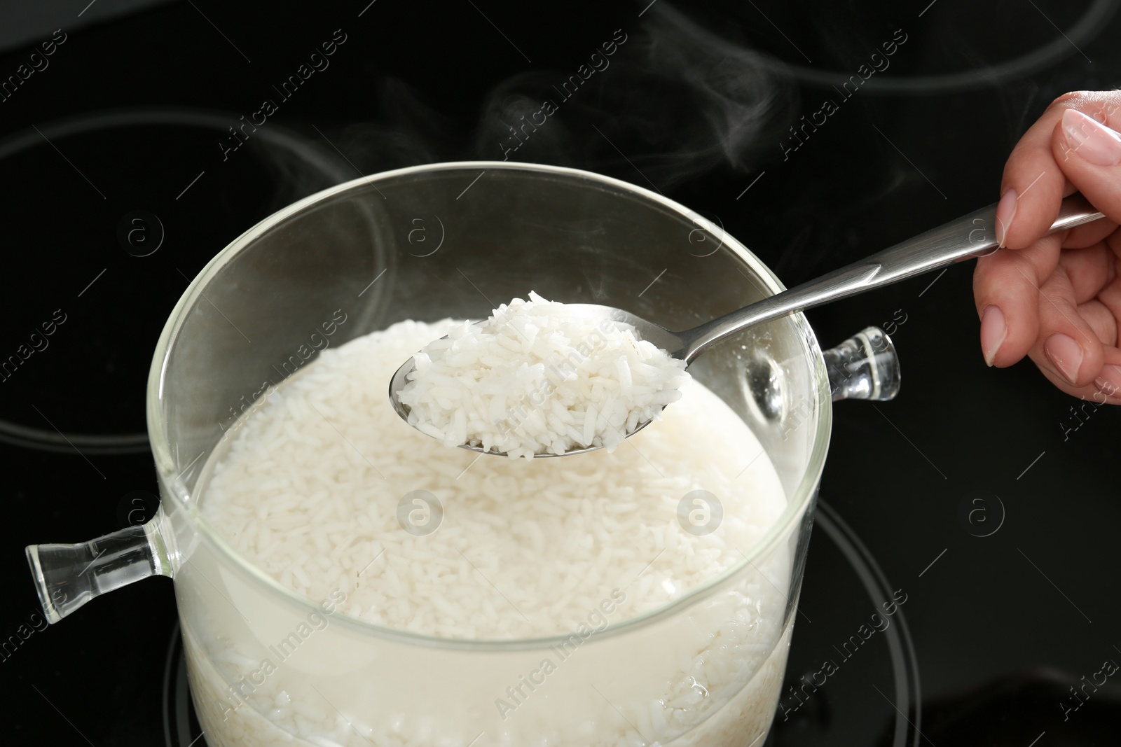 Photo of Woman taking boiled rice from pot, closeup