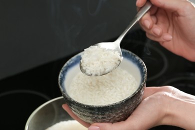 Woman taking boiled rice from pot into bowl, closeup