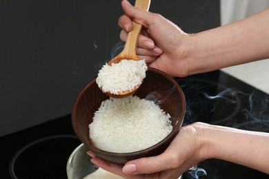 Photo of Woman taking boiled rice into bowl, closeup