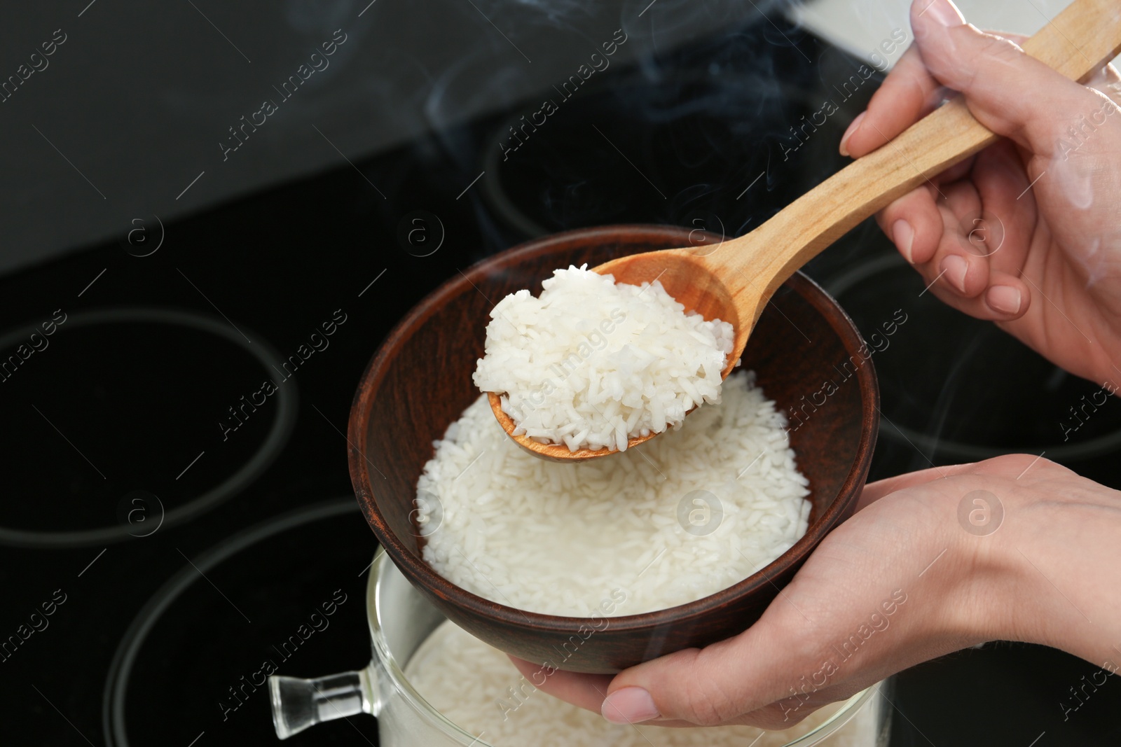 Photo of Woman taking boiled rice into bowl, closeup