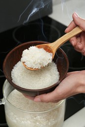 Woman taking boiled rice into bowl, closeup