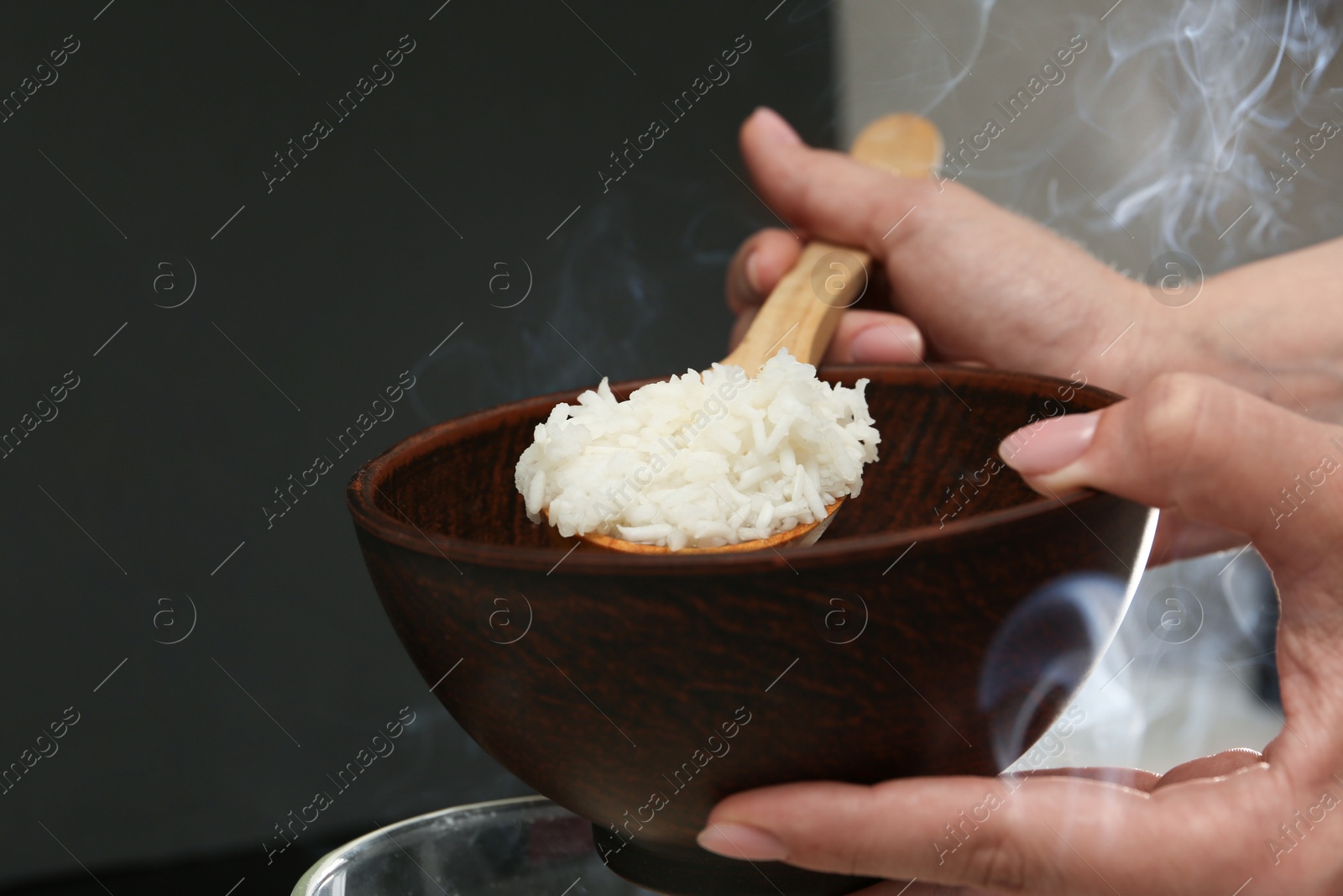 Photo of Woman taking boiled rice into bowl, closeup