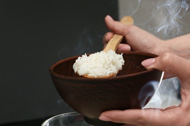 Photo of Woman taking boiled rice into bowl, closeup