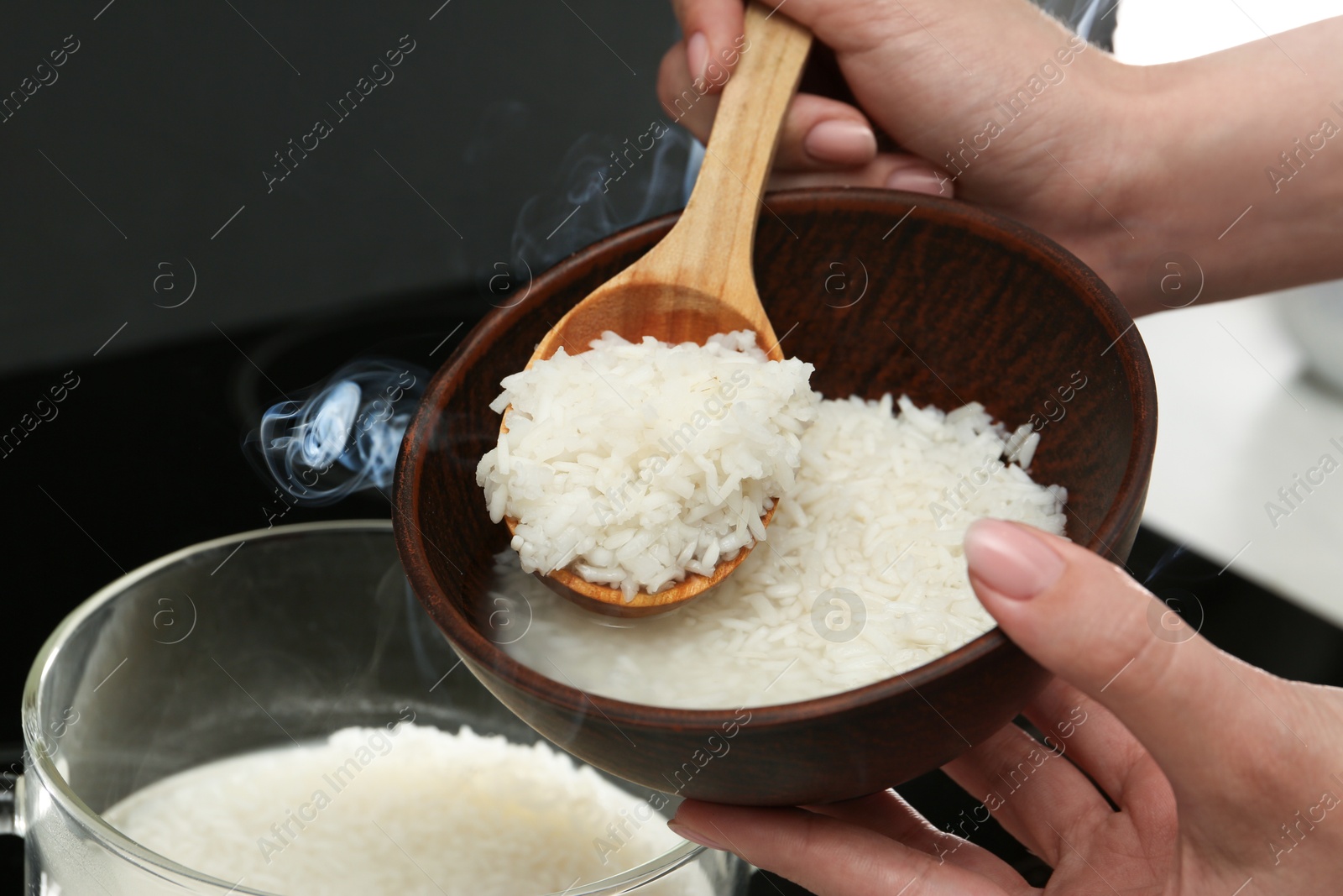 Photo of Woman taking boiled rice into bowl, closeup