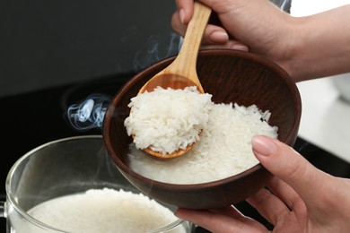 Photo of Woman taking boiled rice into bowl, closeup